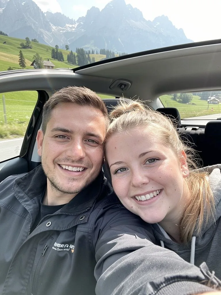 Selfie eines jungen Paares im Auto auf dem Weg durch Bayern, Berge im Hintergrund